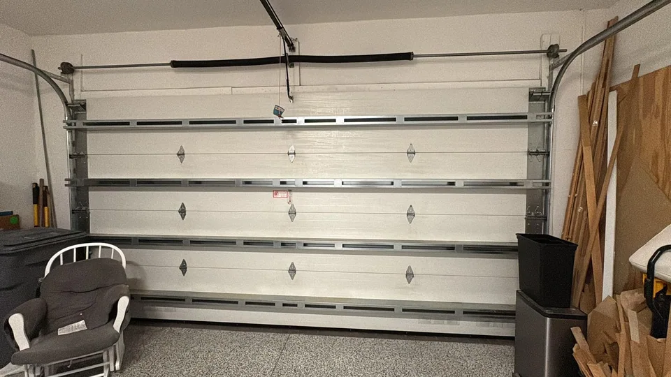Sectional garage door with its torsion spring above the opening